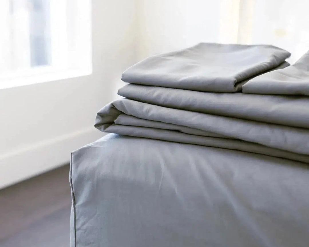 Storm Grey Percale Sheets from the Haven Clean Sleep Bundle, neatly folded on a bed, highlighting their soft, breathable cotton fabric