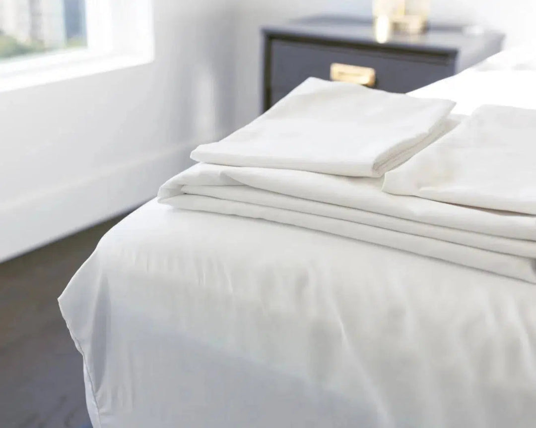 Crisp and Cool Percale Sheets from the Haven Clean Sleep Bundle, neatly folded on a bed, showcasing their soft, breathable cotton fabric