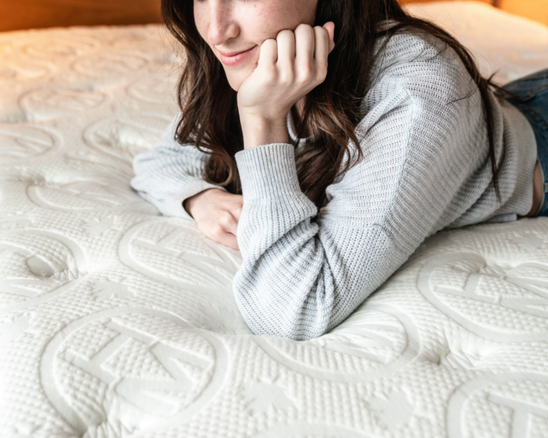 Woman comfortably resting on the Haven LUX Pillowtop Hybrid mattress, showcasing the luxurious textured surface and plush support for a revitalizing sleep experience.