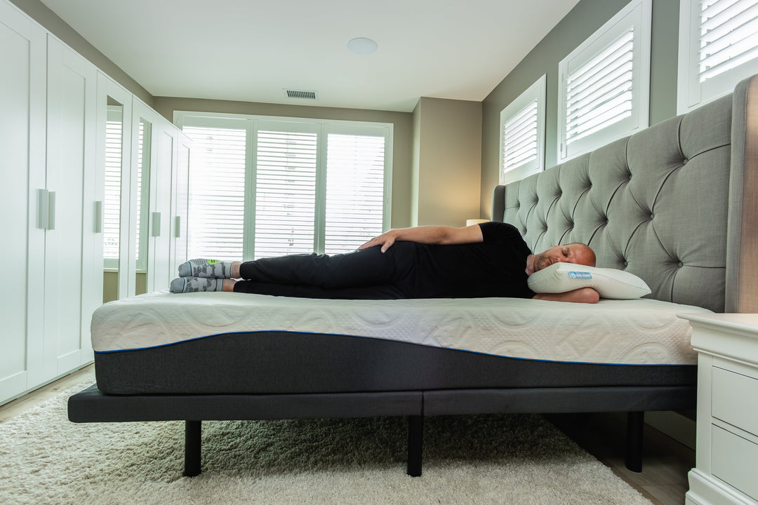 Sleeping on their side on a Haven mattress in a modern bedroom with natural light and tufted headboard.