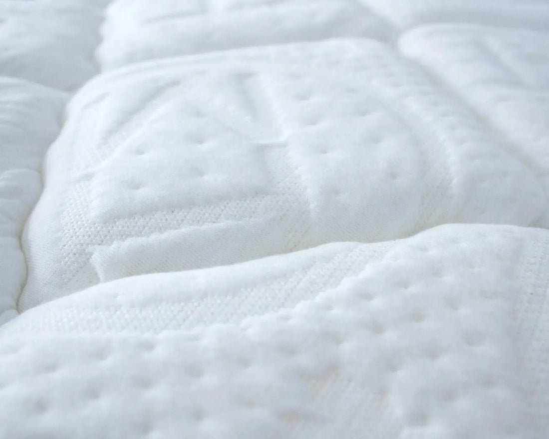 Close-up of a white quilted mattress surface with soft, textured stitching for comfort and support.