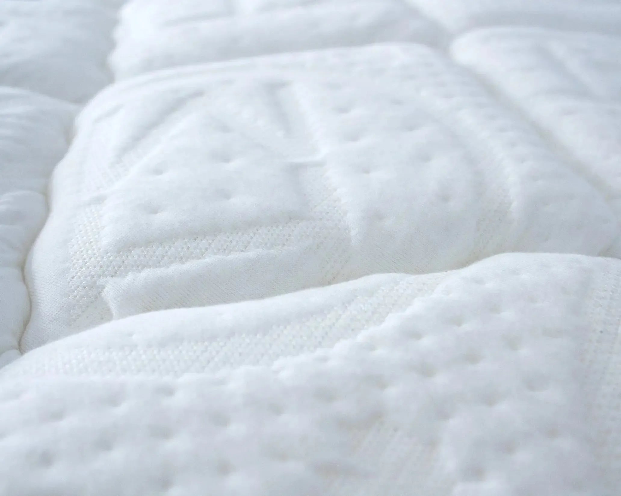 Close-up of a white quilted mattress surface with soft, textured stitching for comfort and support.