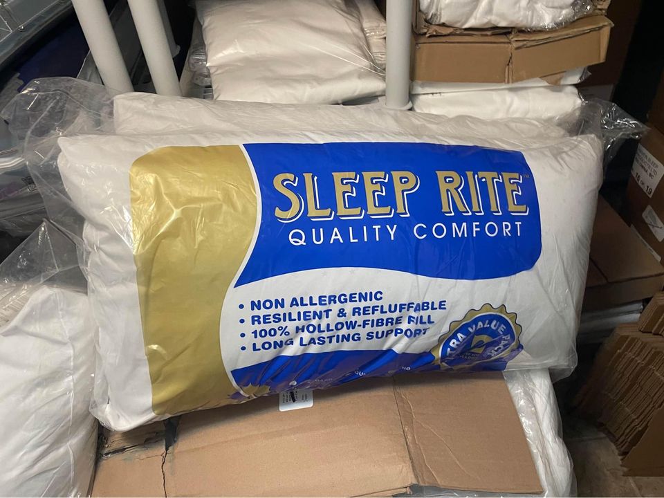 Sleep Rite Poly Pillow in original packaging, featuring a blue and gold label with the text 'Quality Comfort' and key features such as 'Non Allergenic,' 'Resilient & Refluffable,' and '100% Hollow-Fibre Fill,' displayed in a storage area with other pillow packages.