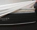 Person placing a smooth and lightweight mattress protector on a Haven Sleep Co. mattress, highlighting its waterproof, hypoallergenic, and breathable features. The protector has deep pockets and is made with some natural bamboo content, offering antimicrobial and allergen-proof protection, made in Canada.