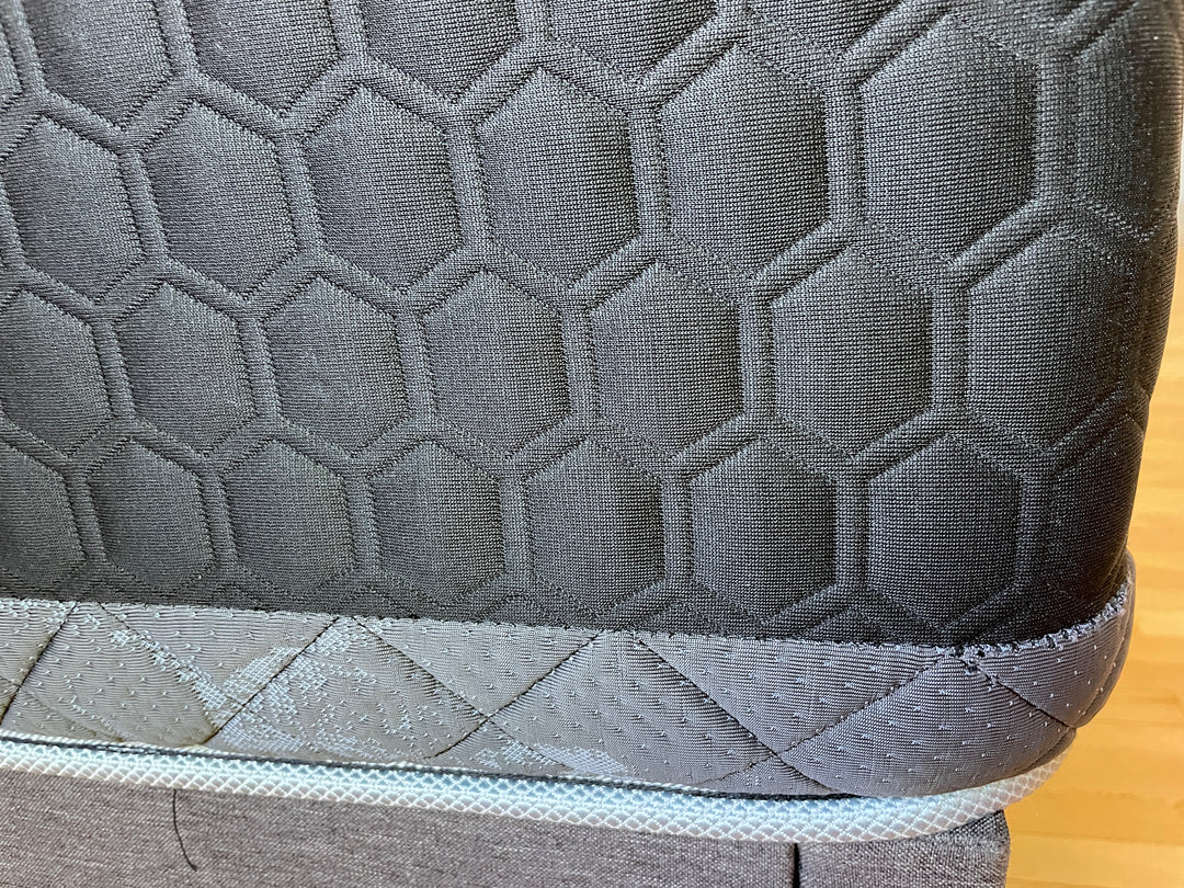 Detailed close-up of the Haven HD Hybrid mattress, focusing on the black and gray honeycomb fabric pattern. The texture showcases the high-quality materials used in this mattress, designed for plus-size sleepers. The image highlights the intricate stitching and durable construction, emphasizing the mattress's ability to provide firm and extra-firm support.