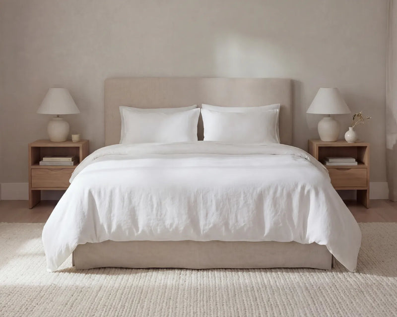 Neatly made bed with white bedding in a bedroom setting.