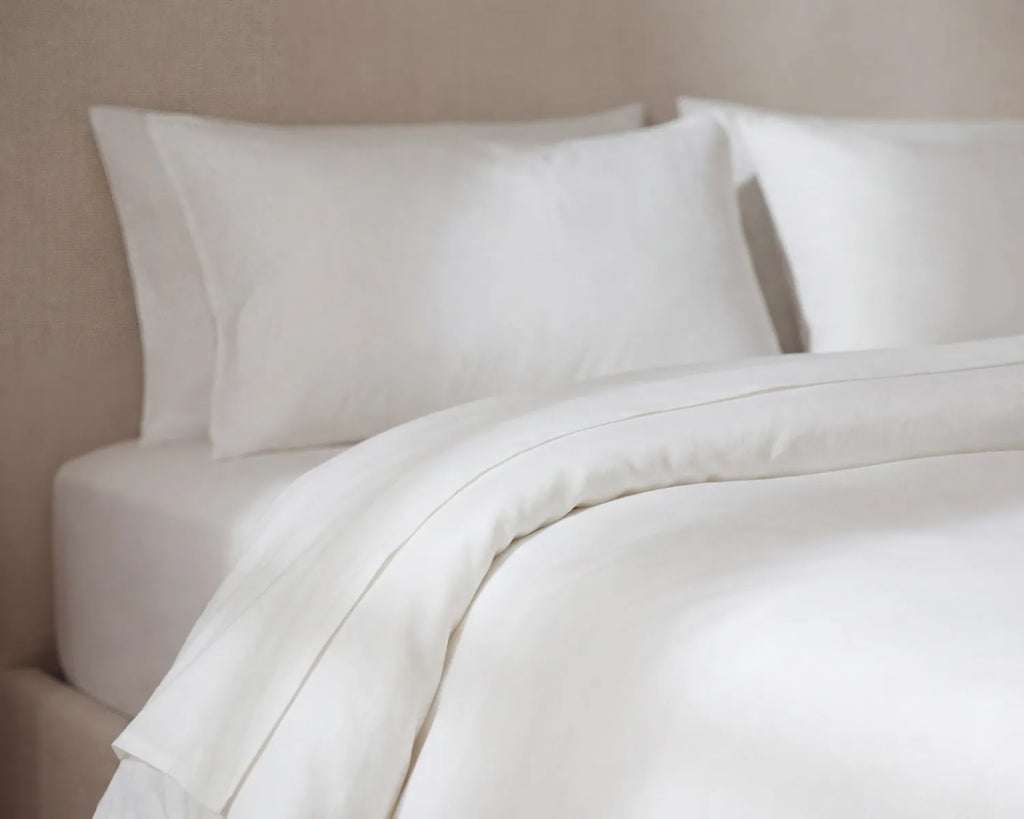 White bedding set with pillows on a neutral background