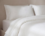 White bedding set with pillows on a neutral background