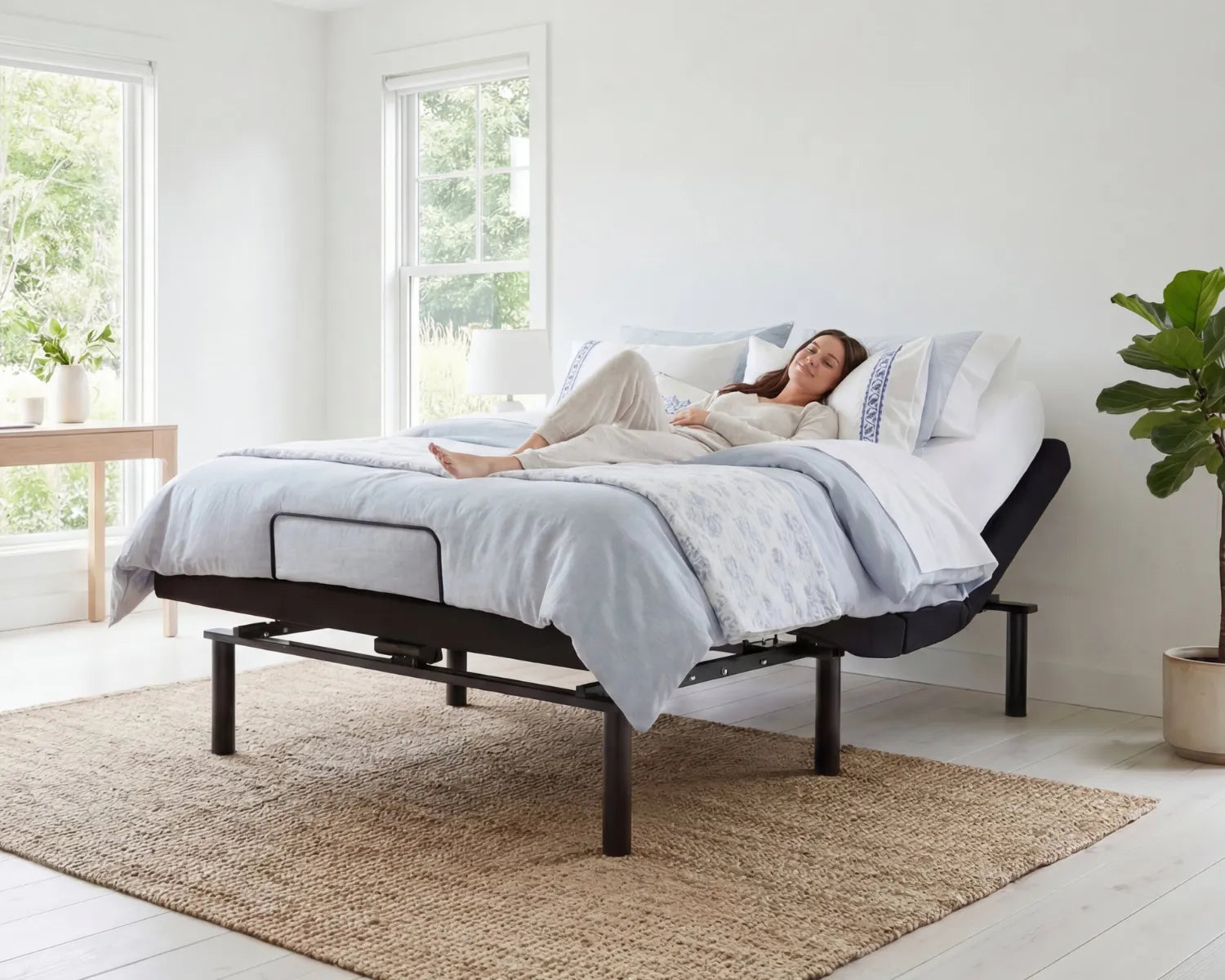 Woman lying on a adjustable bed in a bright bedroom with large windows.