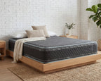 Gray mattress on a wooden bed frame against a white brick wall.