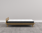 Wooden bed frame with mattress on a gray floor and wall
