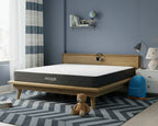 Hiber mattress on a wooden bed frame in a room with a teddy bear and backpack.