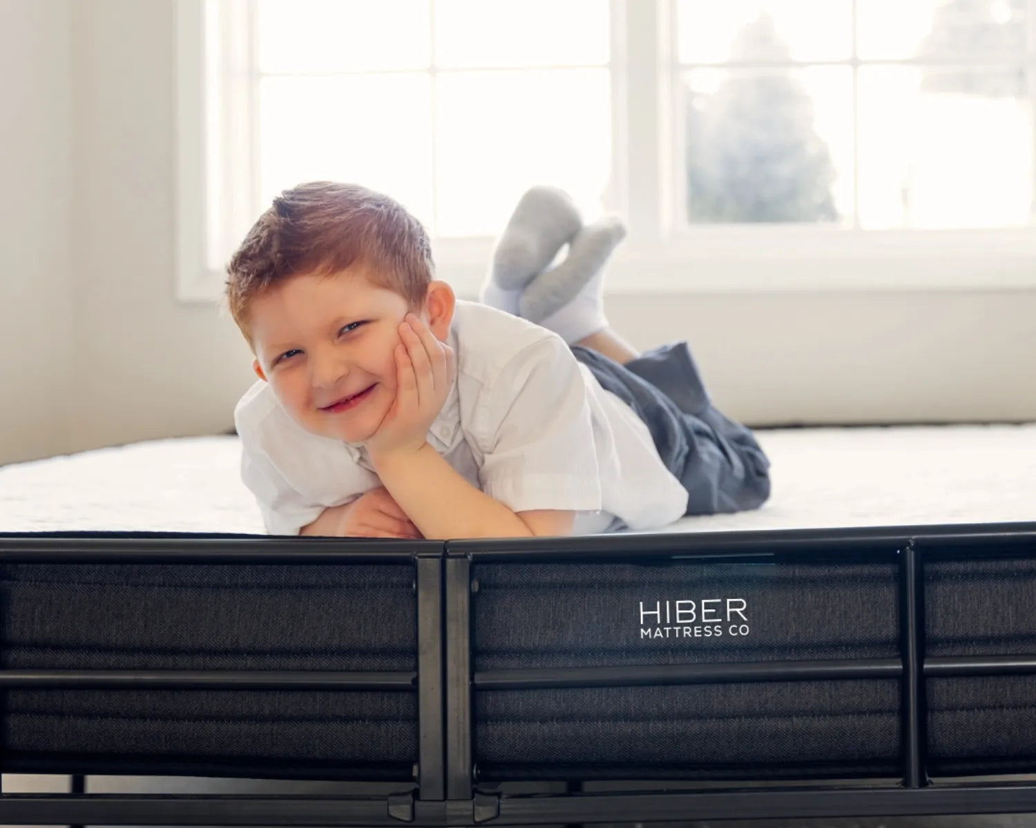 Child lying on a Hiber Mattress Co bed with a bright room in the background