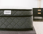 Gray quilted mattress on a bed with 'Haven Sleep Co.' label in a bedroom setting.