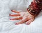 Hand with textured sleeve on a the white Haven mattress top 
