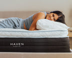 Woman lying on Haven Sleep Co. mattresses with a pillow, smiling.