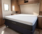 Mattress with 'HAVEN' branding in a compact living space with wooden cabinets and a window.