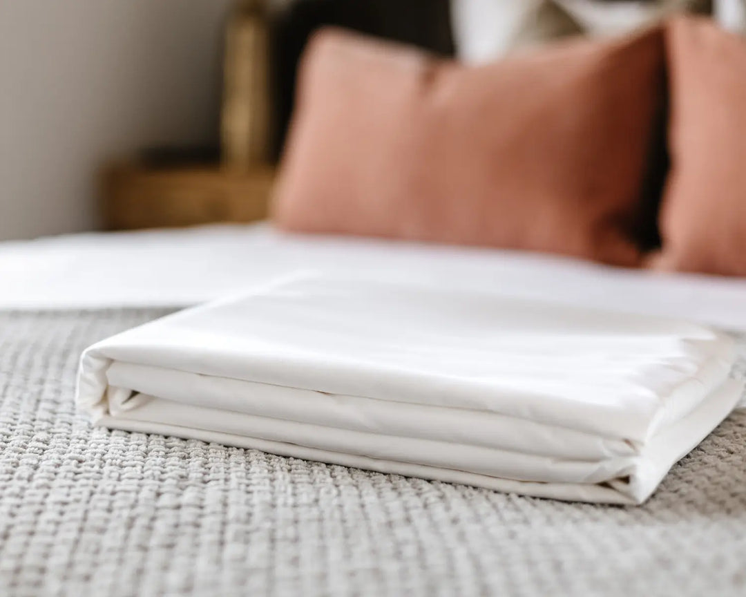 White folded blanket on a bed with brown pillows