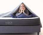 Smiling woman under blanket on HIBER8 Canadian-made mattress, showcasing plush comfort.