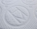 A closeup shot of an H and M letter encapsulated by a circle embroidered on a mattress.
