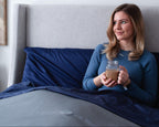 Women sitting up in bed with a cup of coffee and haven sleep company bedface sateen collection in navy and grey